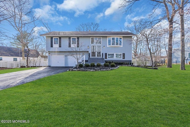 split foyer home with an attached garage, aphalt driveway, a front yard, and fence