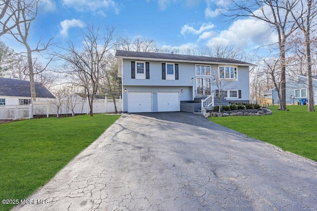 split foyer home featuring an attached garage, aphalt driveway, fence, and a front lawn