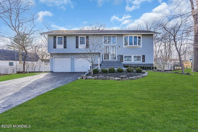 raised ranch featuring driveway, a front lawn, an attached garage, and fence