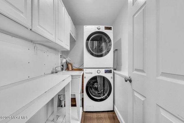 washroom with cabinet space and stacked washer and clothes dryer