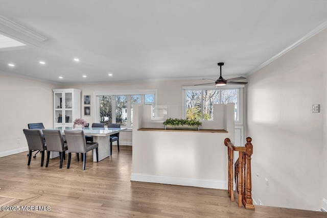 dining space with ornamental molding, a wealth of natural light, baseboards, and light wood finished floors