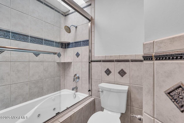 bathroom featuring tiled shower / bath, tile walls, and toilet