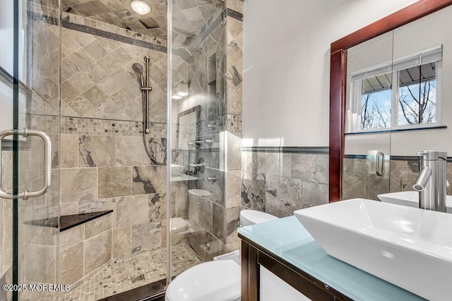 full bath with tile walls, toilet, wainscoting, a shower stall, and vanity