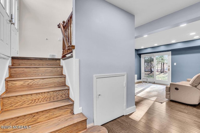 staircase featuring baseboards, wood finished floors, and recessed lighting