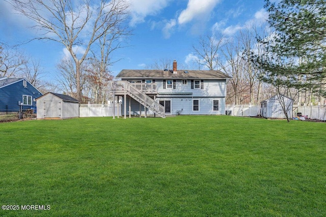 rear view of house with a fenced backyard, a storage shed, an outdoor structure, a yard, and stairway