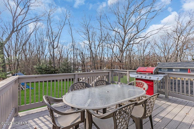 wooden deck with outdoor dining area, a grill, and a lawn