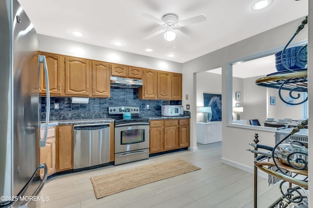 kitchen with under cabinet range hood, light wood-style floors, appliances with stainless steel finishes, decorative backsplash, and brown cabinetry
