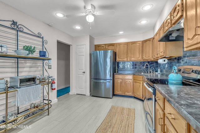 kitchen with under cabinet range hood, tasteful backsplash, stainless steel appliances, and a sink