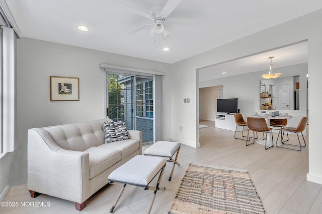 living room with a ceiling fan, recessed lighting, baseboards, and light wood finished floors