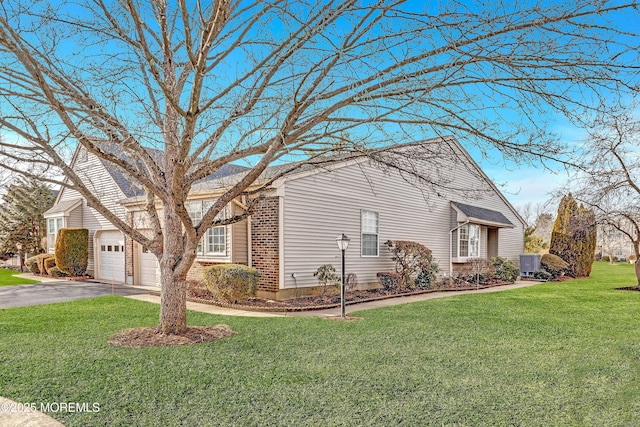 view of home's exterior with aphalt driveway, brick siding, a yard, central air condition unit, and a garage