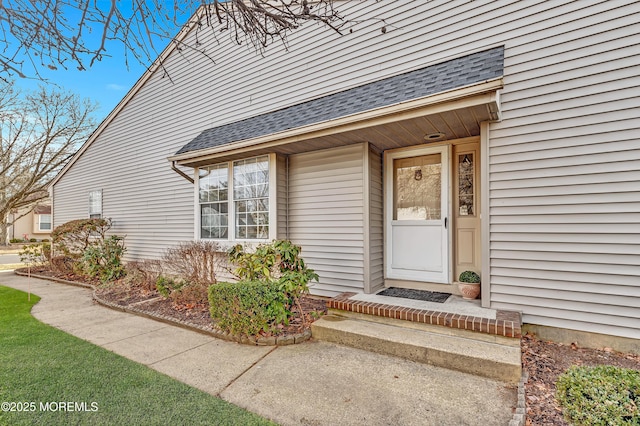 doorway to property featuring roof with shingles