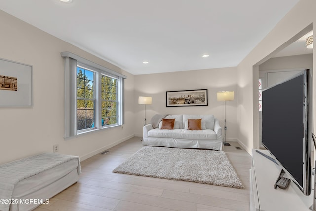 living room with baseboards, recessed lighting, visible vents, and light wood-style floors