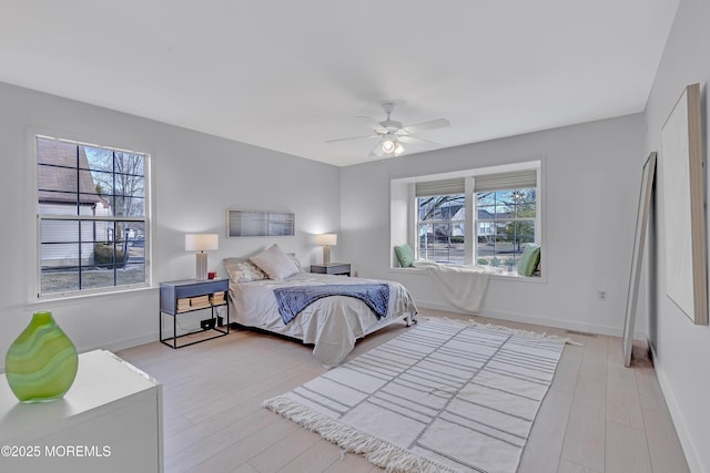 bedroom featuring ceiling fan, light wood-type flooring, visible vents, and baseboards