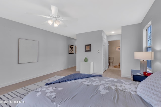 bedroom with ceiling fan, connected bathroom, baseboards, and wood finished floors