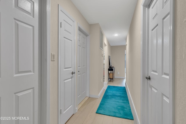hall featuring light wood-style floors and baseboards