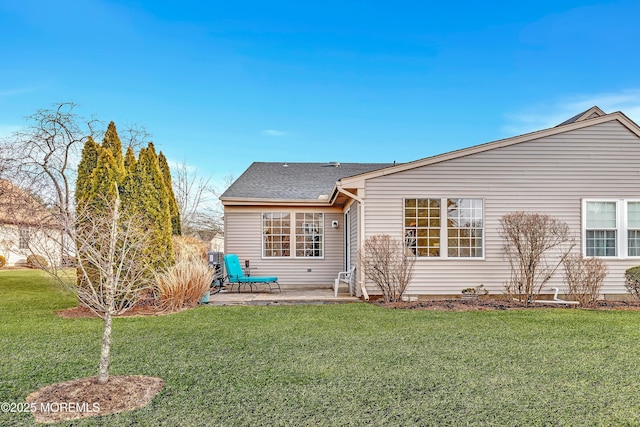 rear view of house featuring roof with shingles, a lawn, and a patio area