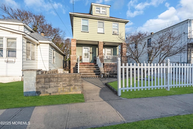 traditional style home featuring covered porch, brick siding, a fenced front yard, and a front lawn