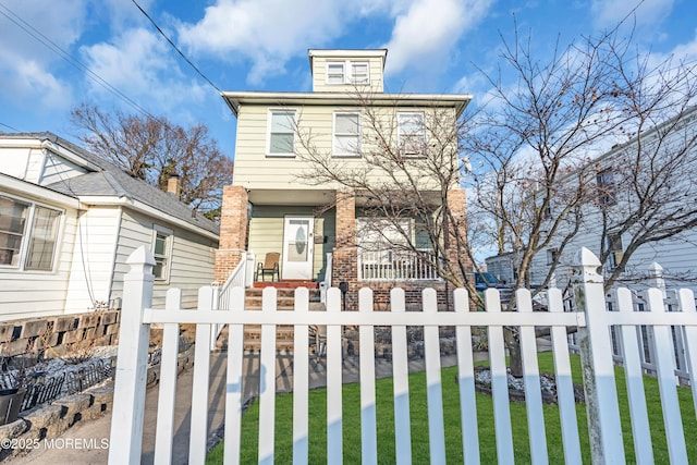 american foursquare style home with a fenced front yard, a porch, and brick siding