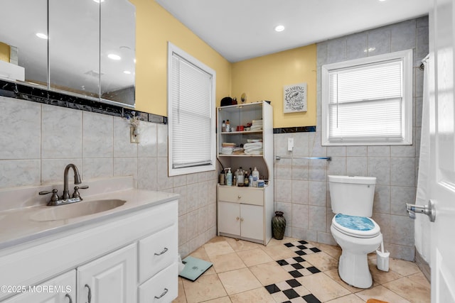 bathroom with toilet, tile patterned floors, tile walls, and vanity