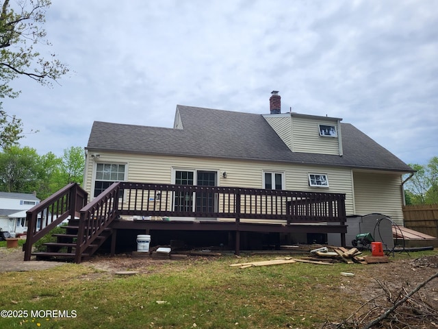 rear view of property featuring a shingled roof, a yard, a chimney, and a wooden deck