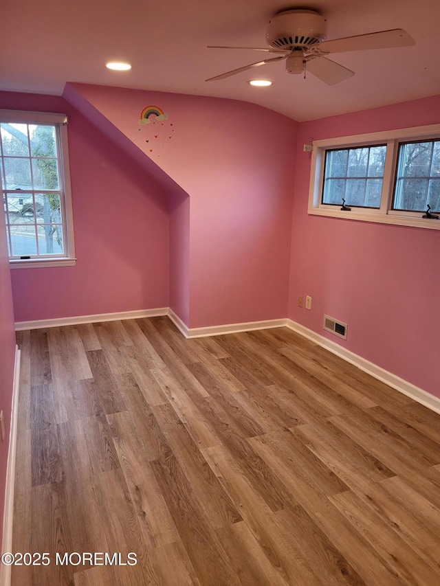 additional living space with baseboards, visible vents, ceiling fan, and wood finished floors