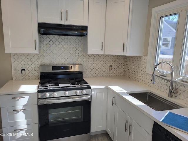 kitchen with tasteful backsplash, stainless steel gas range, under cabinet range hood, white cabinetry, and a sink