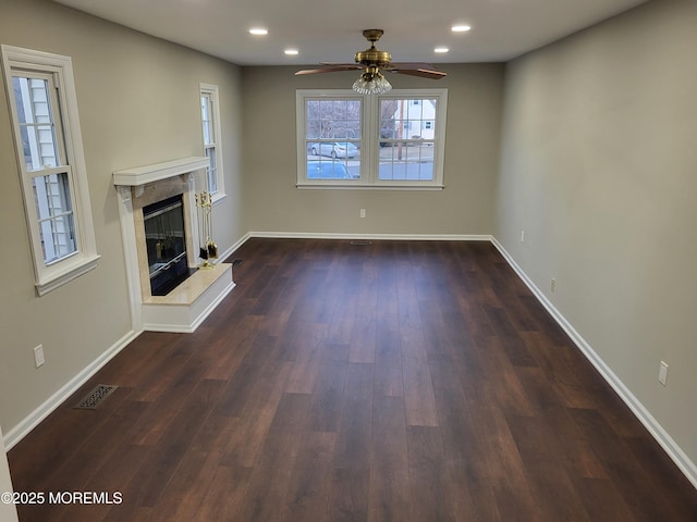 unfurnished living room with baseboards, a premium fireplace, visible vents, and dark wood-type flooring