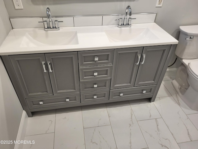 bathroom with marble finish floor, a sink, and toilet