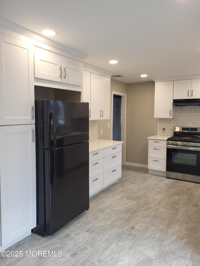 kitchen with stainless steel range with gas cooktop, light countertops, freestanding refrigerator, white cabinets, and under cabinet range hood