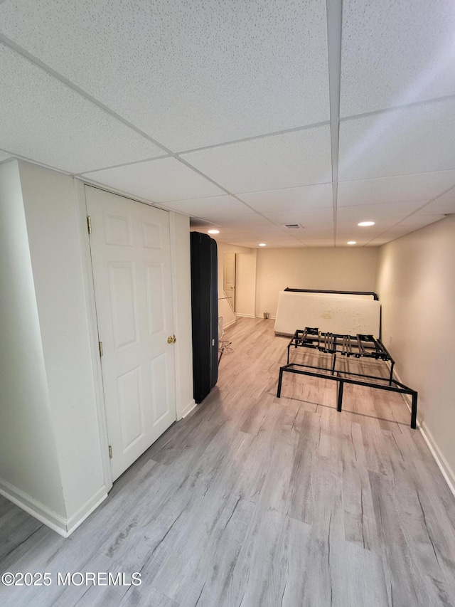 recreation room with a paneled ceiling, light wood finished floors, and baseboards