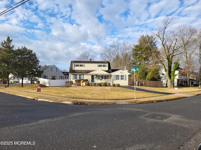 traditional home featuring a front yard, fence, and a chimney