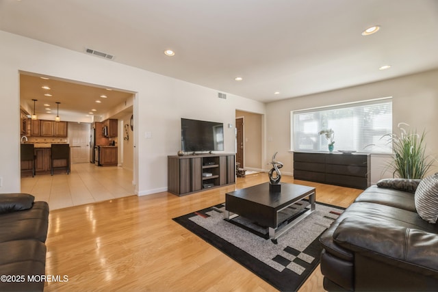 living room with baseboards, light wood-style flooring, visible vents, and recessed lighting