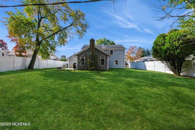 rear view of property with a fenced backyard, a lawn, and a chimney