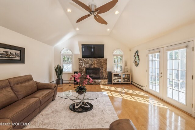 living area featuring a baseboard radiator, a premium fireplace, vaulted ceiling, french doors, and light wood-type flooring