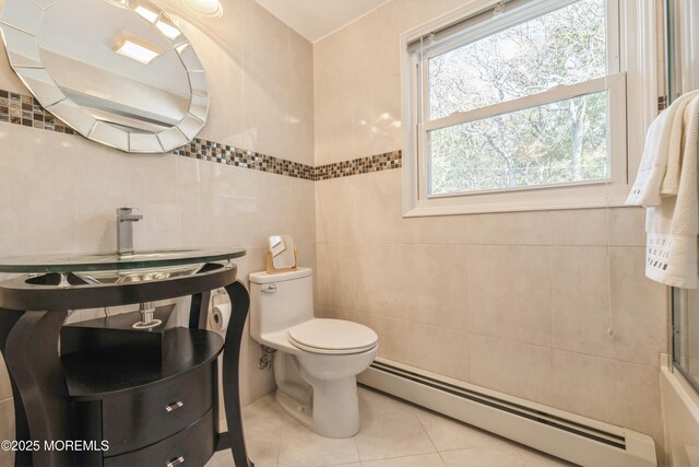 bathroom featuring toilet, a baseboard heating unit, tile walls, and tile patterned floors