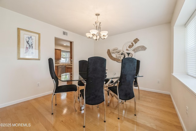 dining space with a notable chandelier, light wood finished floors, visible vents, and baseboards