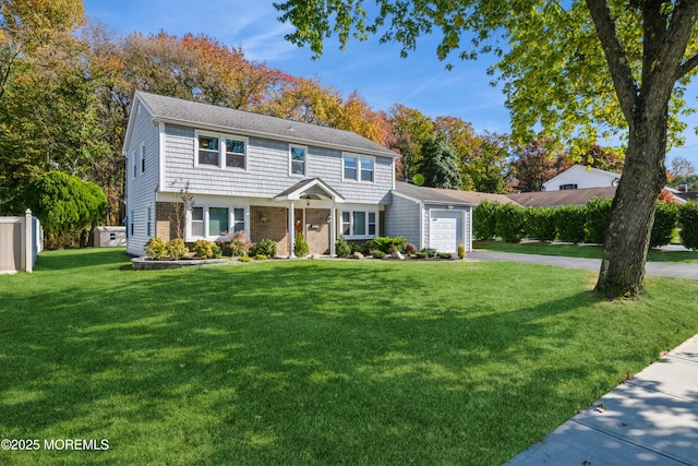 colonial-style house featuring a garage, driveway, fence, a front lawn, and brick siding