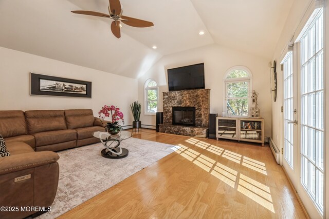 living area with lofted ceiling, baseboard heating, a fireplace, and wood finished floors