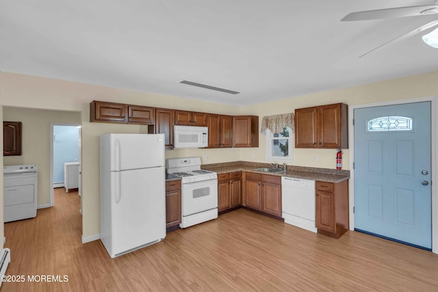 kitchen featuring light wood finished floors, white appliances, washer / clothes dryer, and a sink