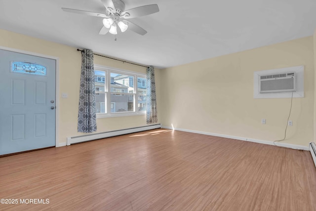 interior space featuring baseboard heating, a wall unit AC, wood finished floors, and baseboards