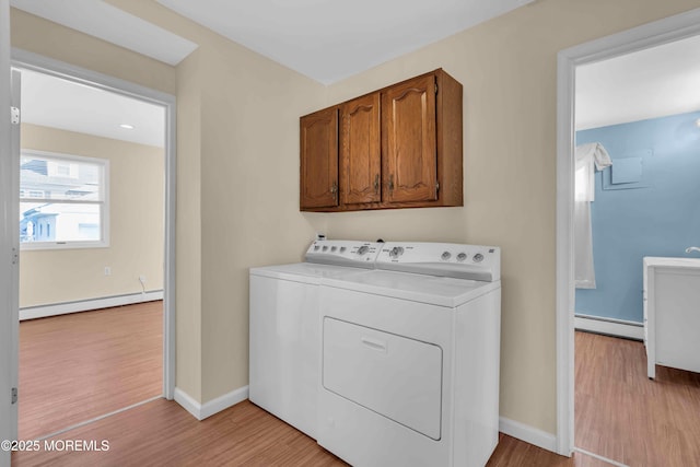 washroom featuring baseboards, a baseboard radiator, light wood-style flooring, and washer and dryer