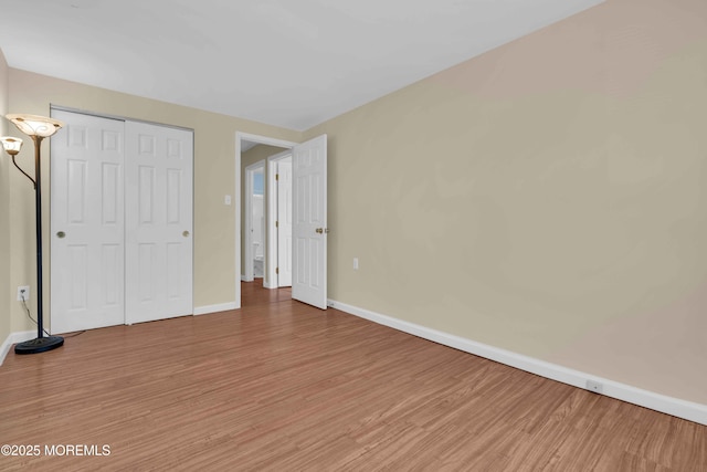 unfurnished bedroom with light wood-style floors, baseboards, and a closet