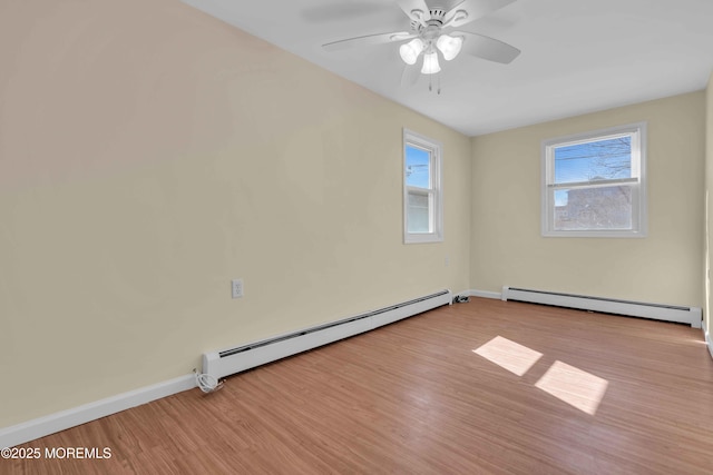 empty room with baseboard heating, a wealth of natural light, and wood finished floors