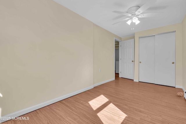 unfurnished bedroom with a ceiling fan, a closet, baseboards, and wood finished floors