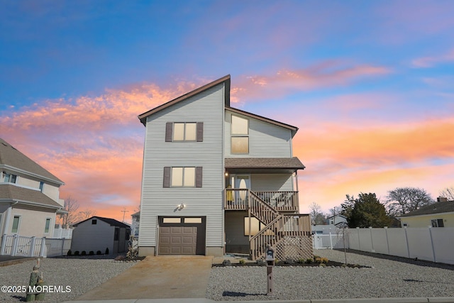 view of front facade with stairs, concrete driveway, an attached garage, and fence