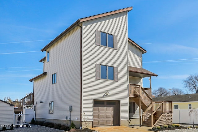 back of house featuring an attached garage, stairs, and fence