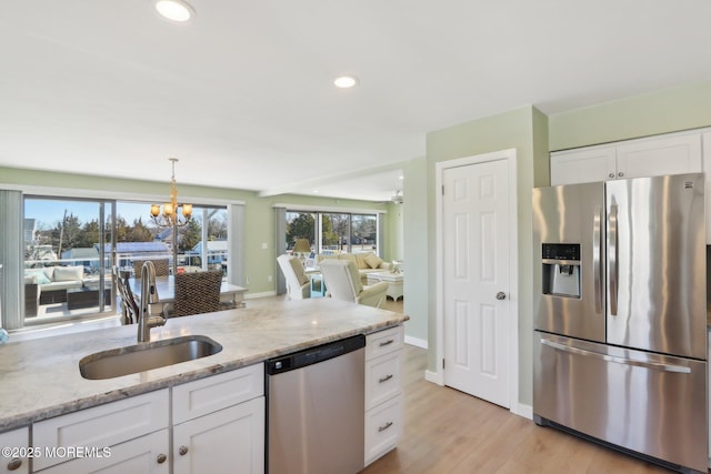 kitchen featuring a sink, white cabinets, light stone counters, and stainless steel appliances