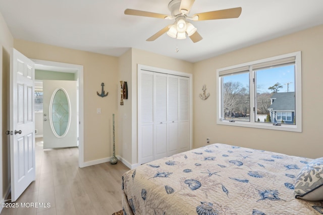 bedroom with a closet, a ceiling fan, light wood-type flooring, and baseboards