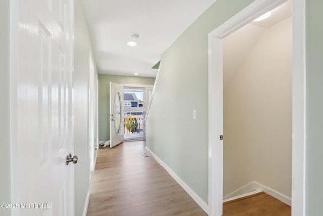 corridor featuring light wood-style flooring and baseboards