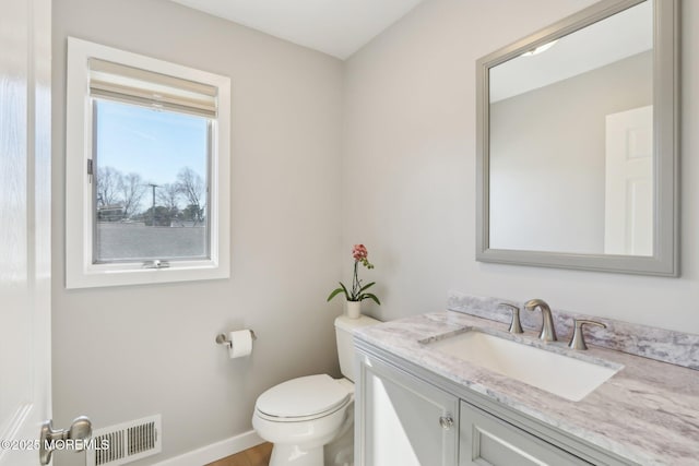 half bathroom featuring visible vents, baseboards, toilet, and vanity